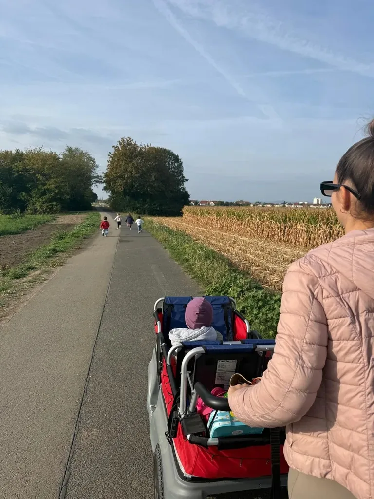 Spaziergang mit Kinderwagen auf einem Weg zwischen Feldern